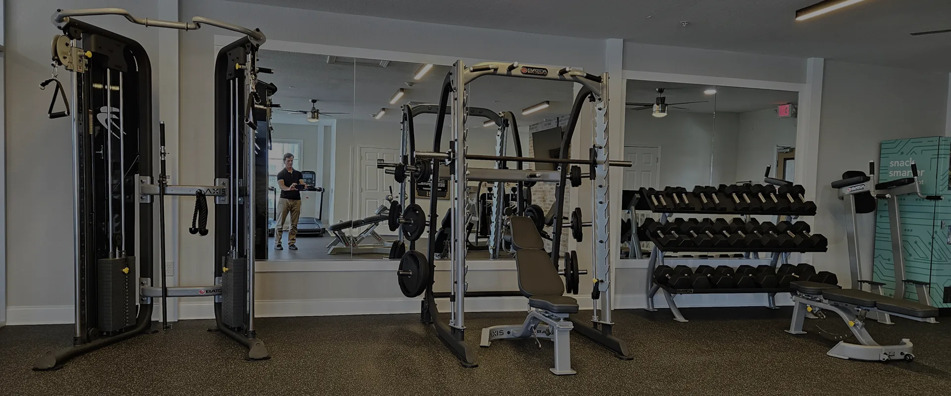 Upscale apartment fitness center with Batca AXIS Free Trainer, adjustable benches, and strength training equipment