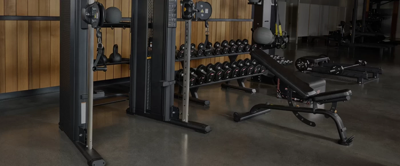 Precor adjustable bench and functional trainer in a premium home gym with dumbbells, wood accents, and modern fitness design